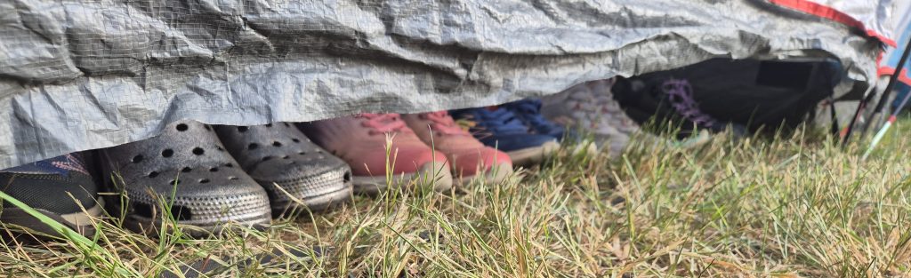 Shoes poking out from under a tent door. #DringyGroupCamp25